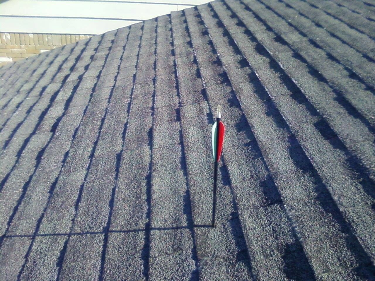 Close-up view of a dark shingled roof, with a small red and white marker sticking up.