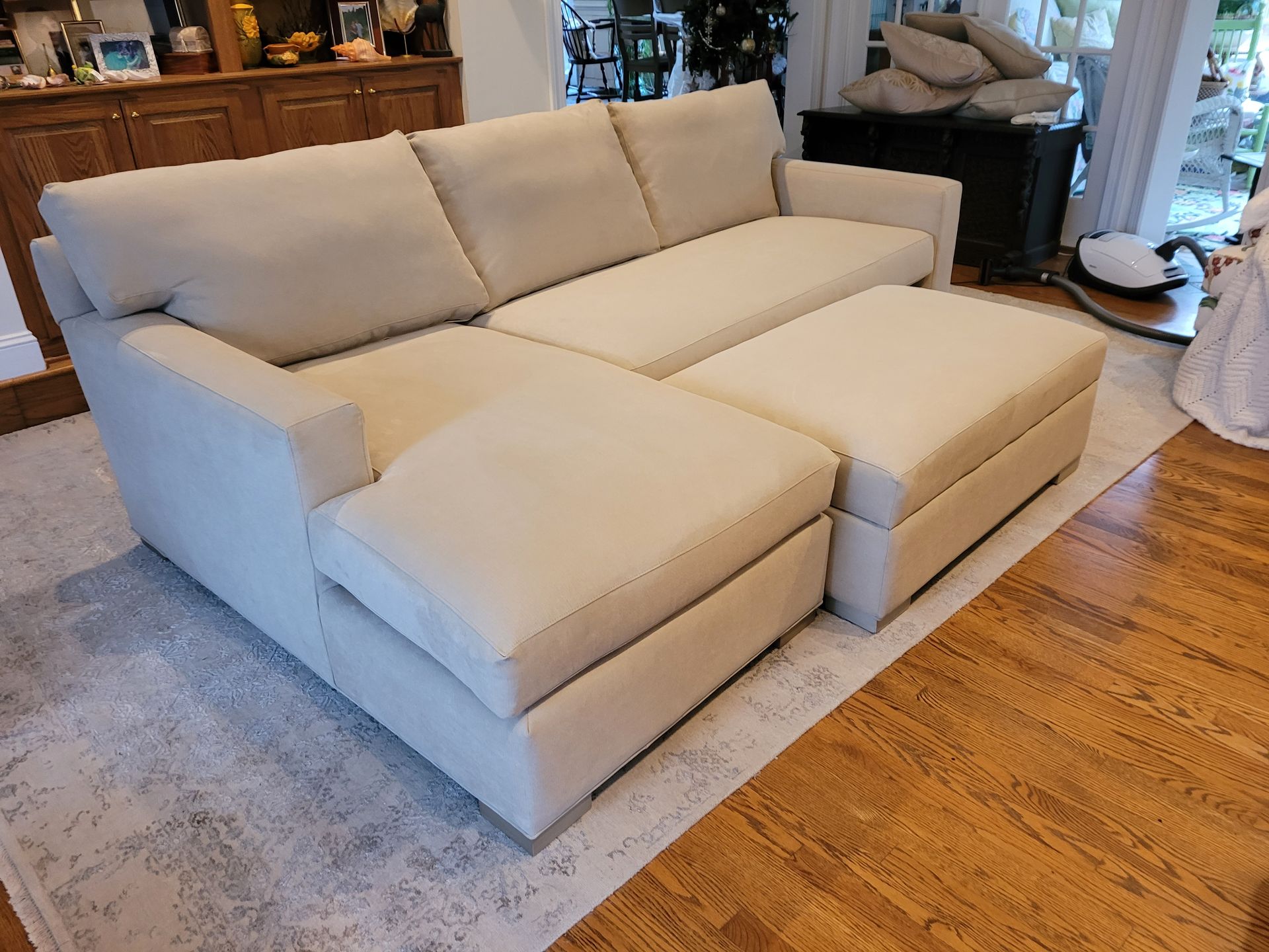 A white sectional couch with two ottomans in a living room.