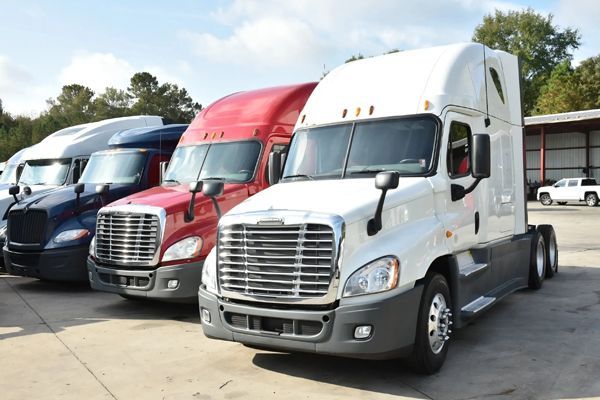 A row of semi trucks are parked in a parking lot.