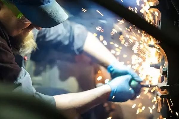 A man is cutting a piece of metal with a pair of scissors.