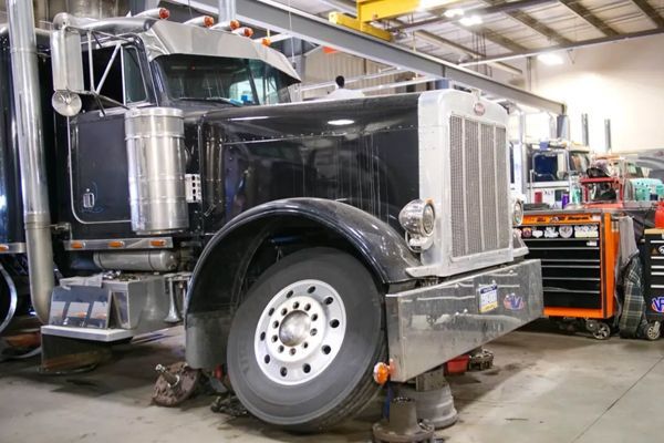 A black and white semi truck is parked in a garage.