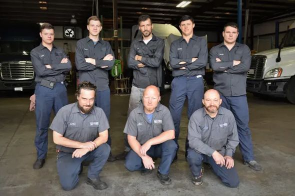 A group of men are posing for a picture in a garage.