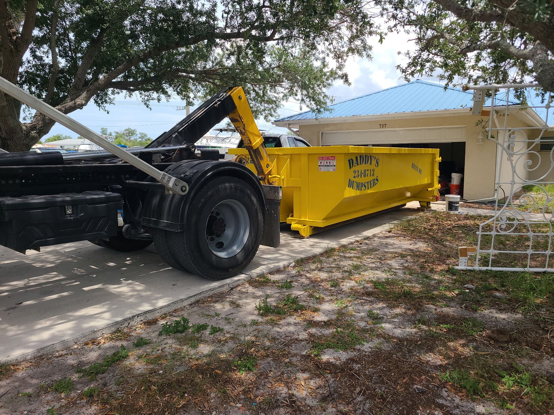 Yellow Daddy's Dumpsters roll-off truck delivering a dumpster in Southwest Florida, providing driveway-safe dumpster rentals for residential and construction cleanup projects.