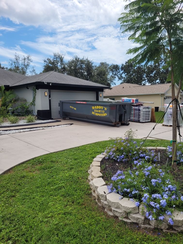  A dumpster is parked in the driveway of a house. Roll-Off Dumpster Rental in Sarasota.