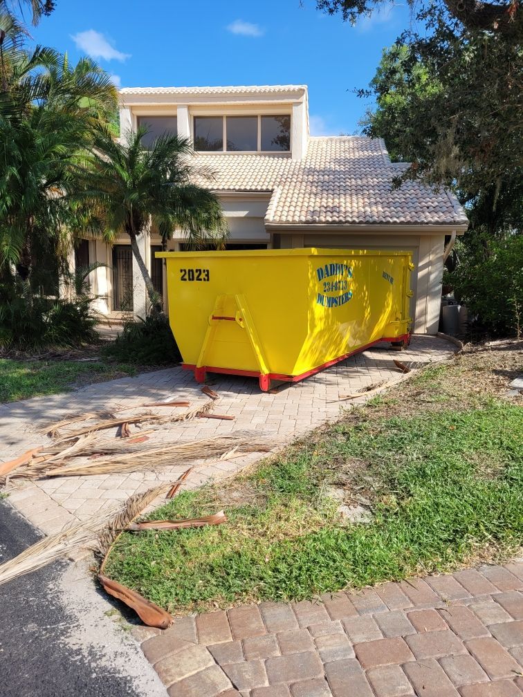 A neat-looking yellow dumpster is parked in front of a house. Roll-Off Dumpster Rental in Sarasota.