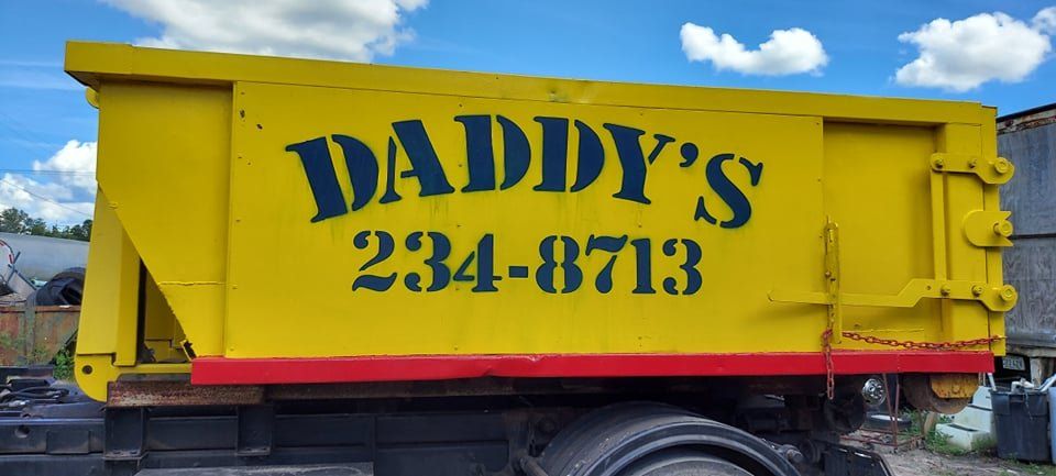 A yellow dumpster with the words Daddy's written on it. Roll-Off Dumpster Rental in Sarasota.