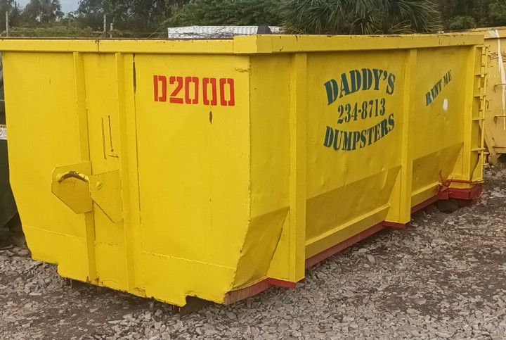 A yellow dumpster is sitting on top of a gravel road. Roll-Off Dumpster Rental in Sarasota.