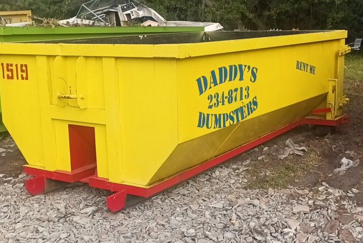 A yellow dumpster from Daddy's Dumpsters is parked on the side of the road. Roll-Off Dumpster Rental in Sarasota.