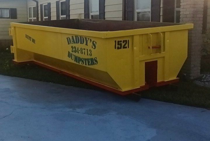 A neat yellow dumpster is parked in front of a house. Roll-Off Dumpster Rental in Sarasota.