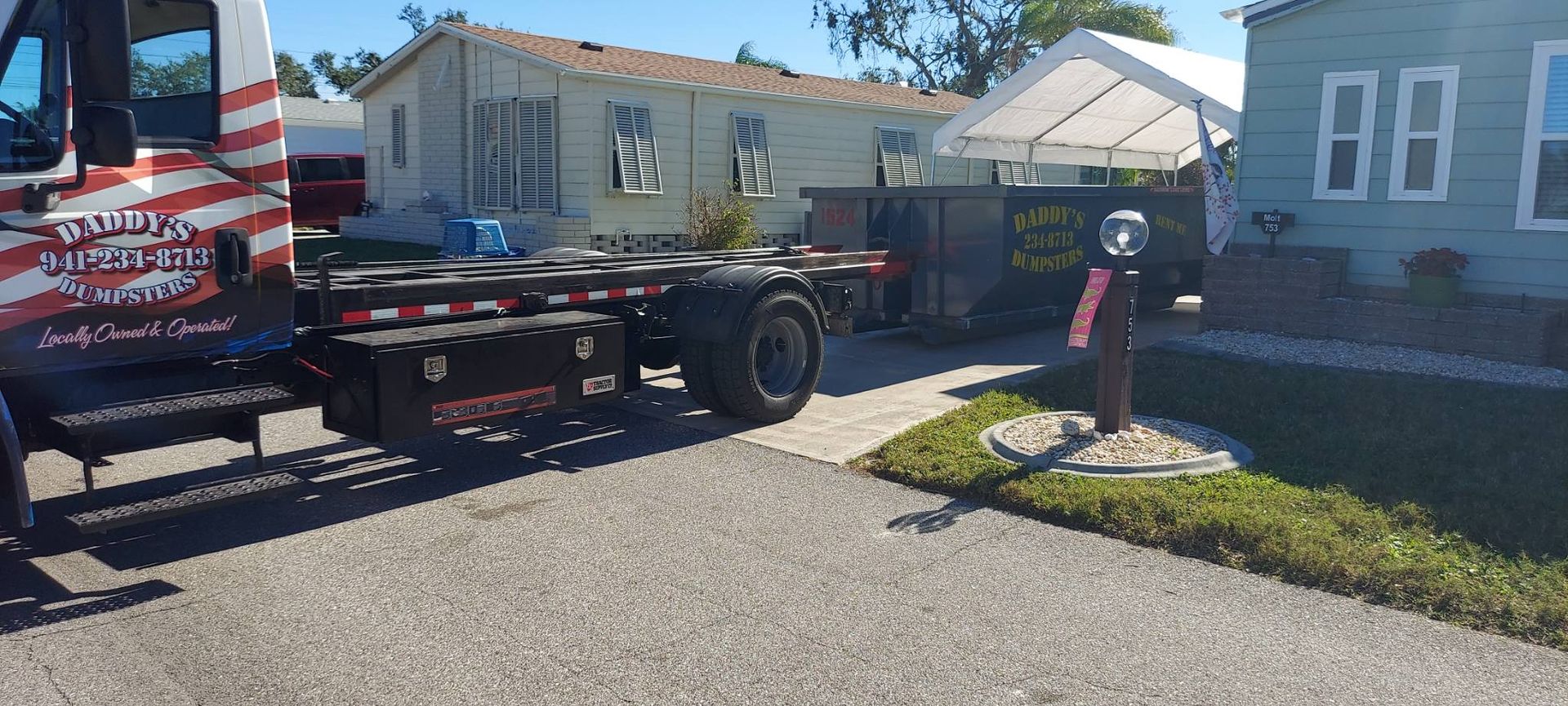 A tow truck is parked in front of a mobile home. Roll-Off Dumpster Rental in Sarasota.