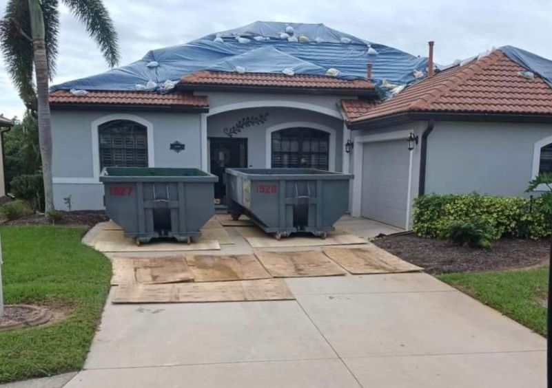 Two dumpsters are parked in front of a house that is being remodeled. Roll-Off Dumpster Rental in Sarasota.