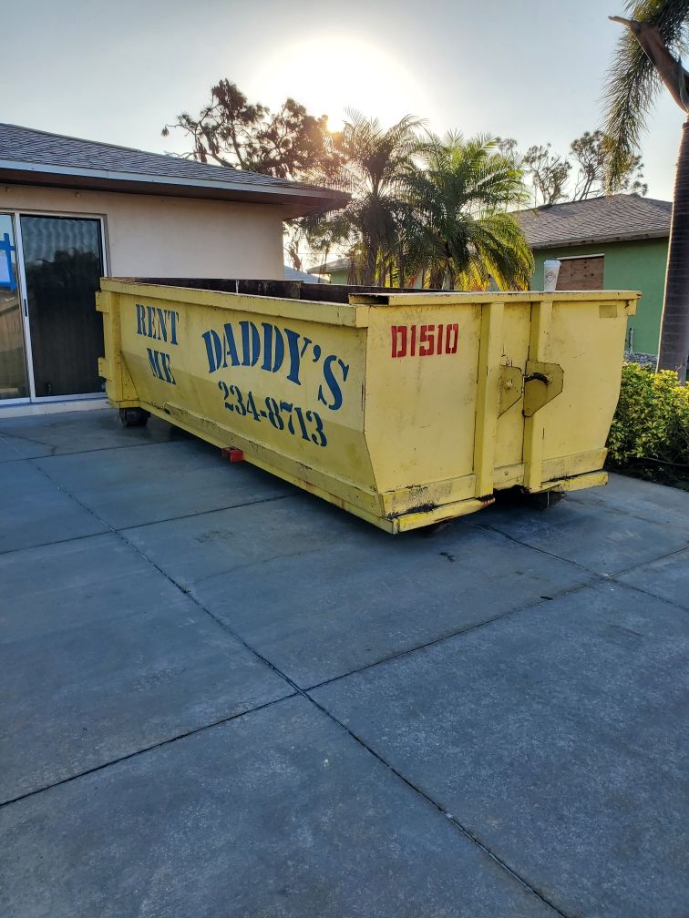 A dumpster is parked in front of a house. Roll-Off Dumpster Rental in Sarasota.