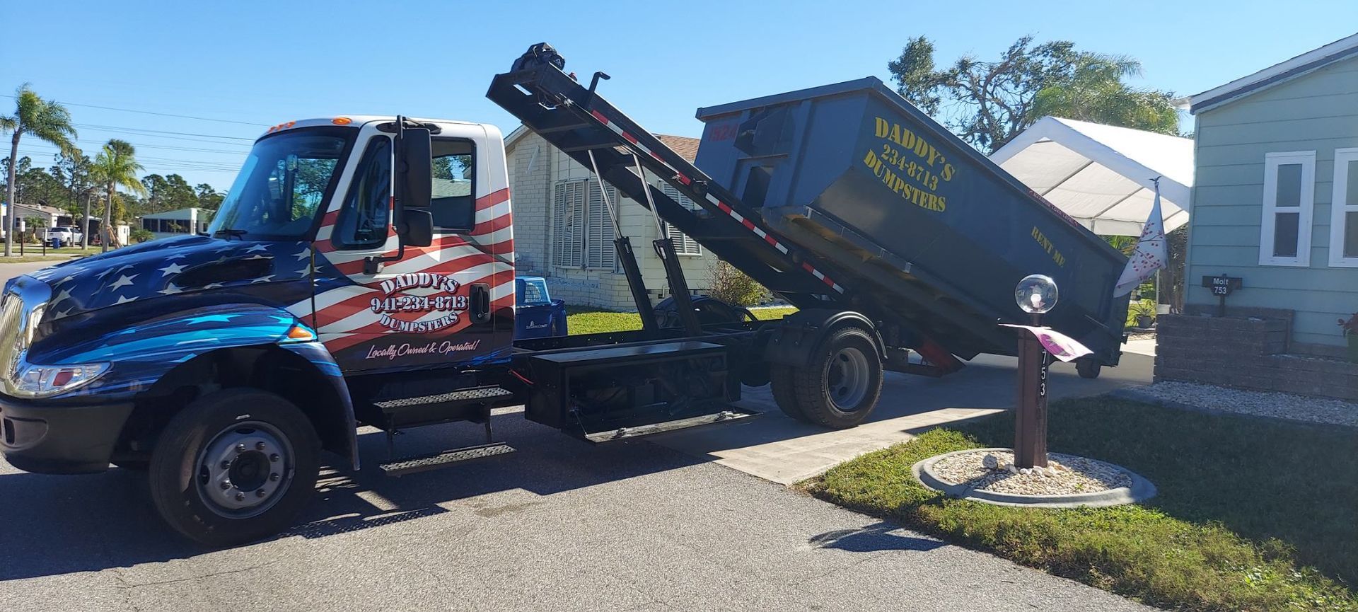 A dump truck is parked on the side of the road next to a house. Roll-Off Dumpster Rental in Sarasota.