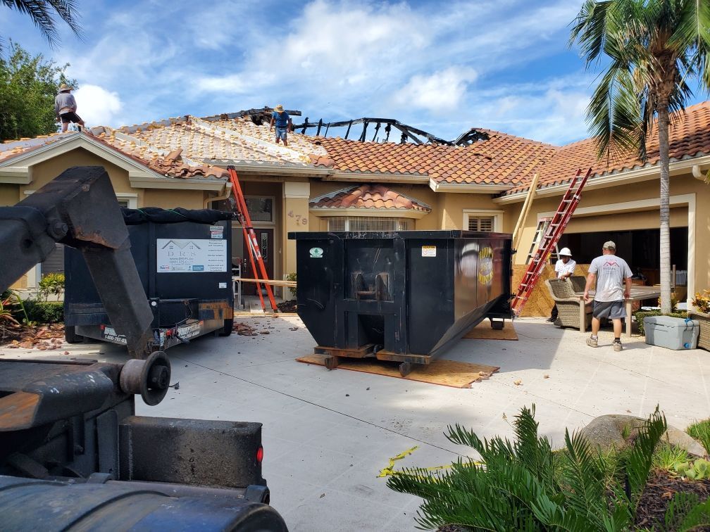 A dumpster is parked in front of a house under construction.
