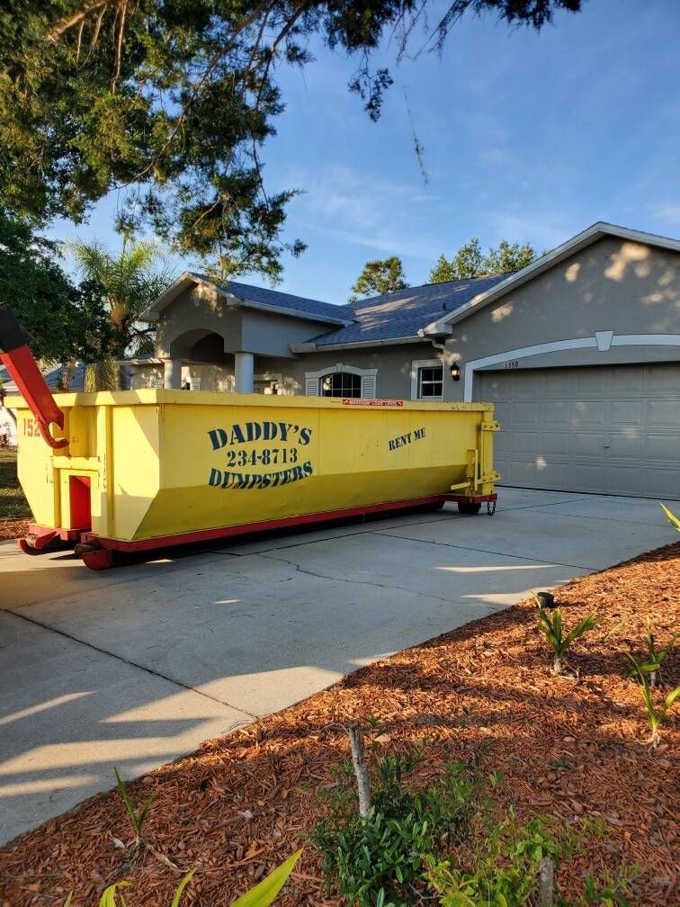 A yellow, neat-looking dumpster is parked in front of a house. Roll-Off Dumpster Rental in Sarasota.