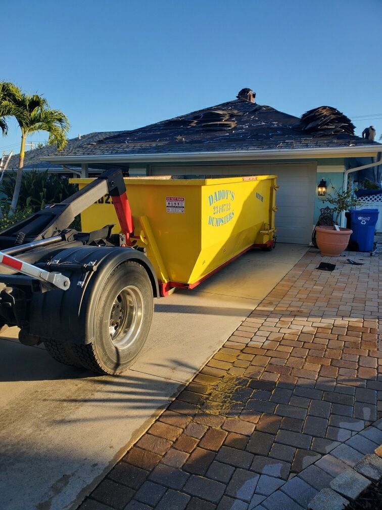 A Daddy's dumpster is parked in front of a house. Roll-Off Dumpster Rental in Sarasota.