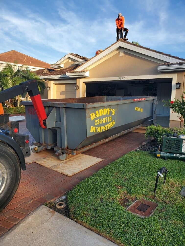 A man is standing on the rooftop of a house. Roll-Off Dumpster Rental in Sarasota.