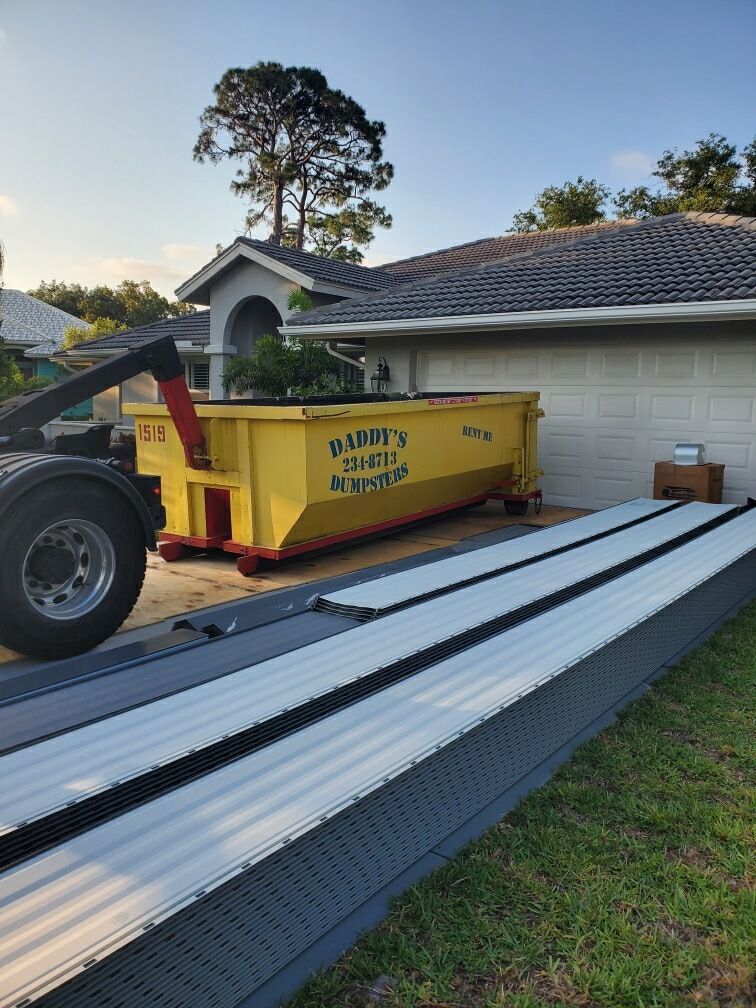 A yellow dumpster is parked in front of a house. Roll-Off Dumpster Rental in Sarasota.