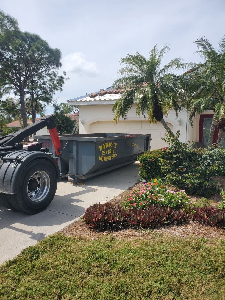 A dumpster is sitting in a driveway next to a house. Roll-Off Dumpster Rental in Sarasota.