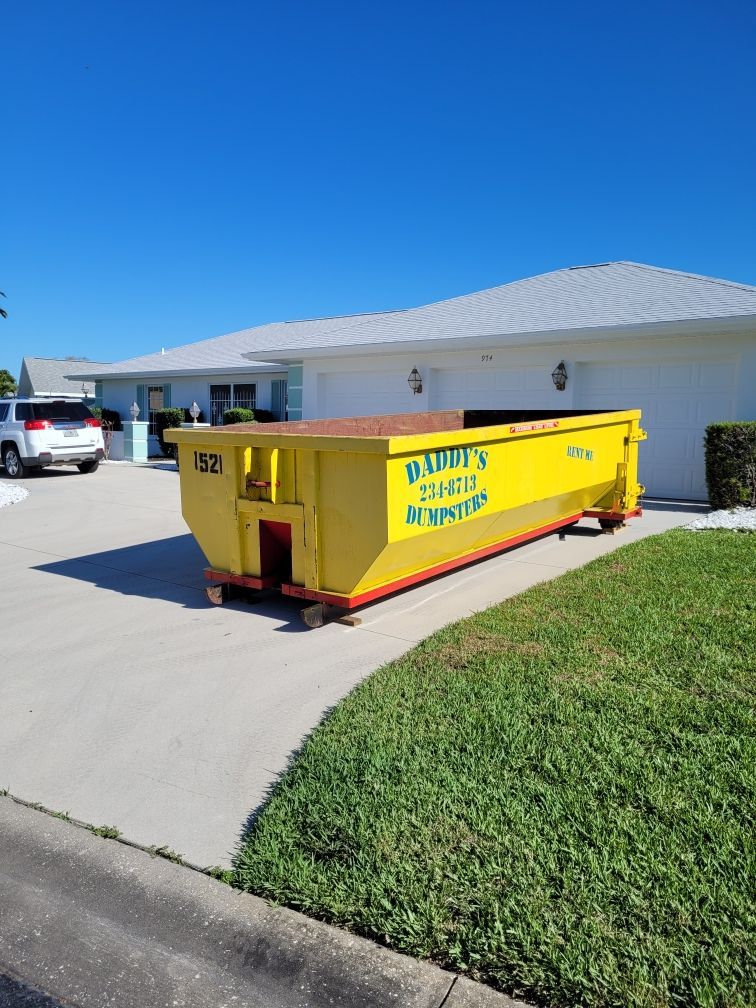 A yellow Daddy's dumpster is parked in front of a house. Roll-Off Dumpster Rental in Sarasota.