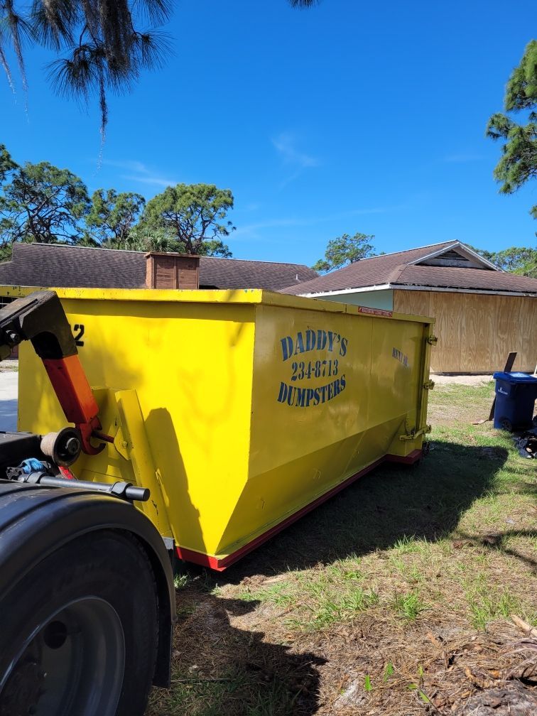 A yellow dumpster is parked in front of a house. Roll-Off Dumpster Rental in Sarasota.