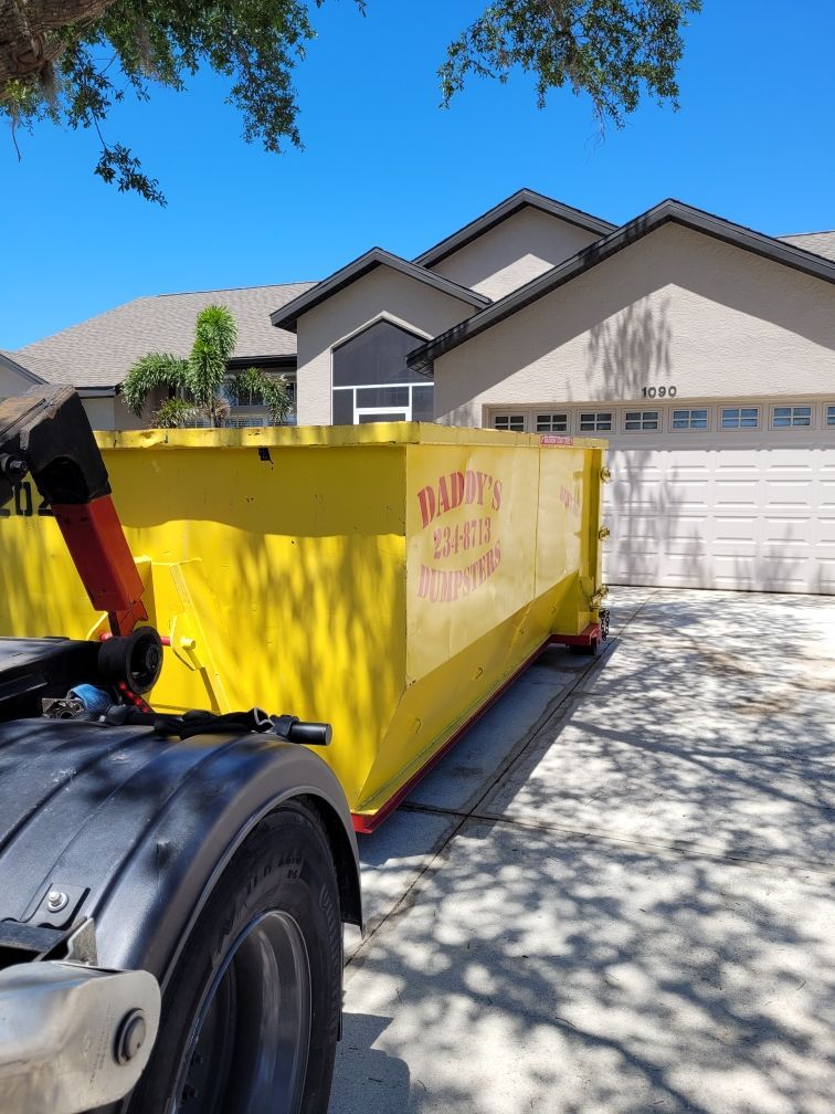 A neat yellow dumpster is parked in front of a house. Roll-Off Dumpster Rental in Sarasota.