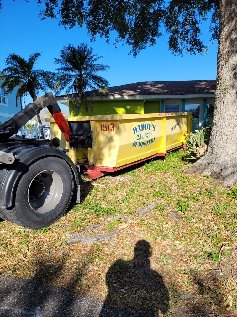A picture of a yellow dumpster, parked in front of a house. Roll-Off Dumpster Rental in Sarasota.