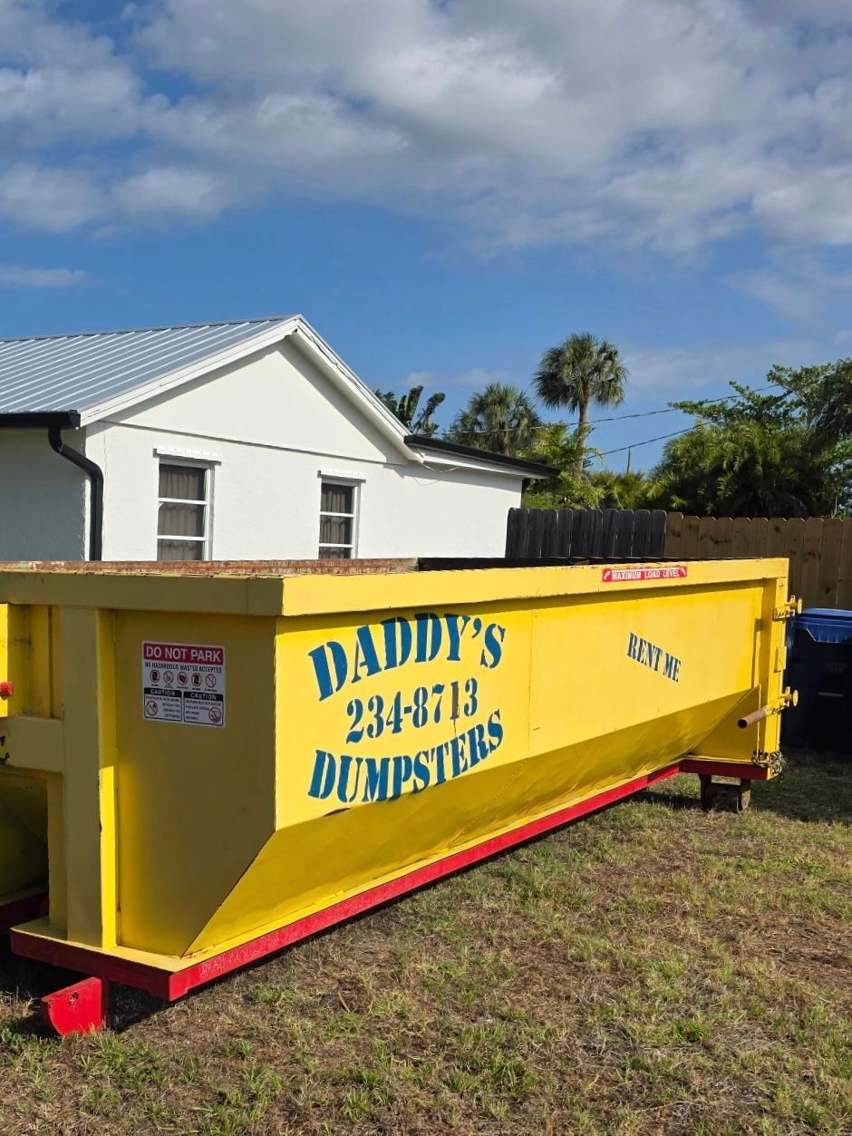 15-yard yellow dumpster trailer with “Daddy’s Dumpsters” logo beside a white house under a blue sky