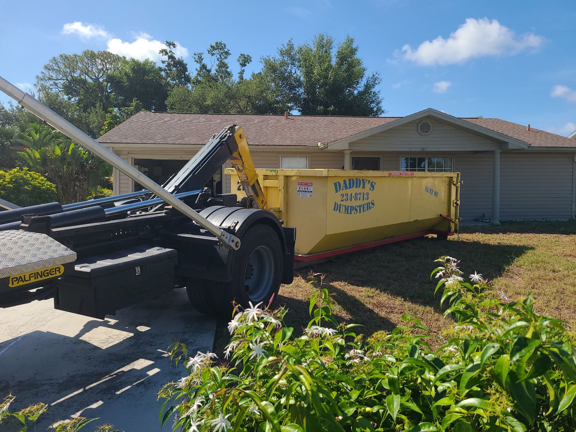 20-yard yellow dumpster on a driveway beside a black truck in front of a suburban house