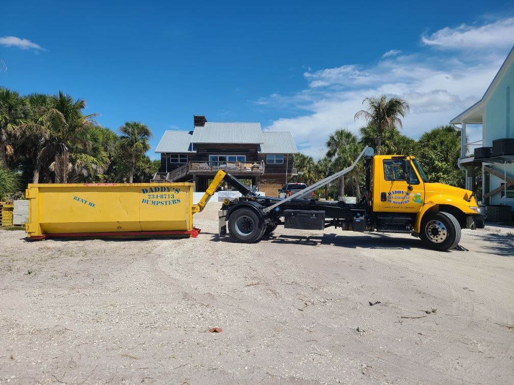 20-yard yellow dump container and truck chassis in a sunny lot under a blue sky