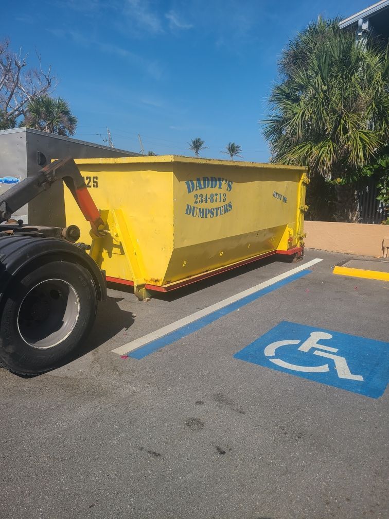 20-yard Yellow dumpster in a parking lot beside a blue accessible parking space marking