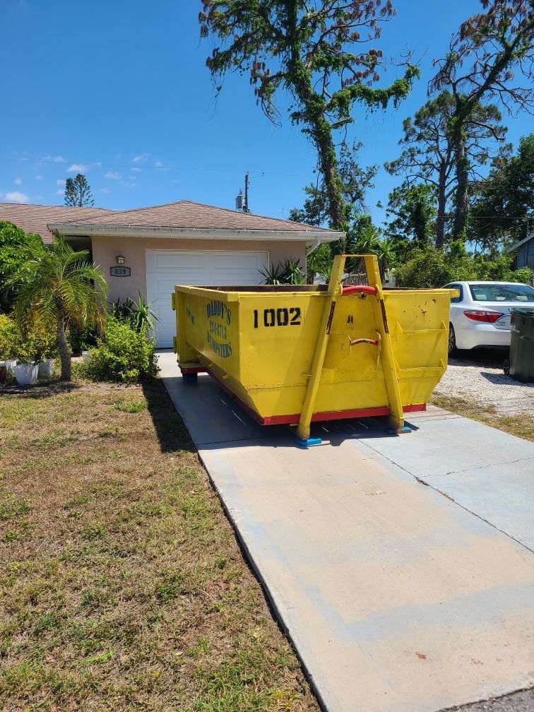 10-yard yellow dumpster on a driveway beside a house under a clear blue sky