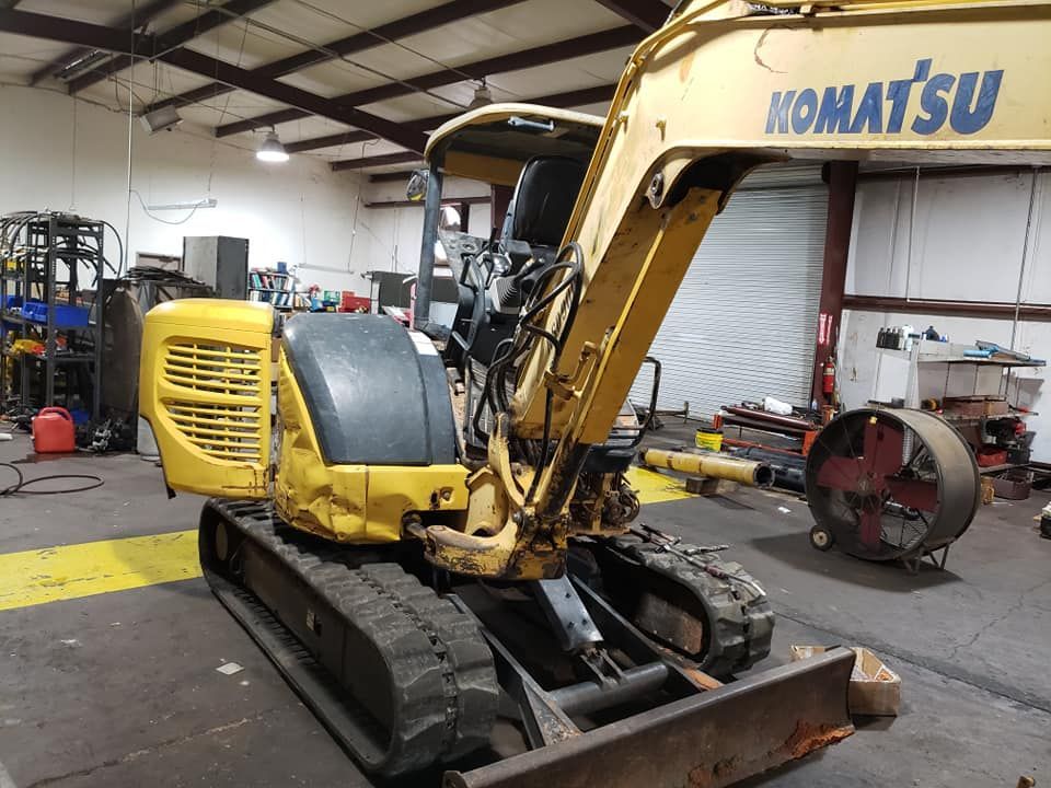 A yellow komatsu excavator is parked in a garage