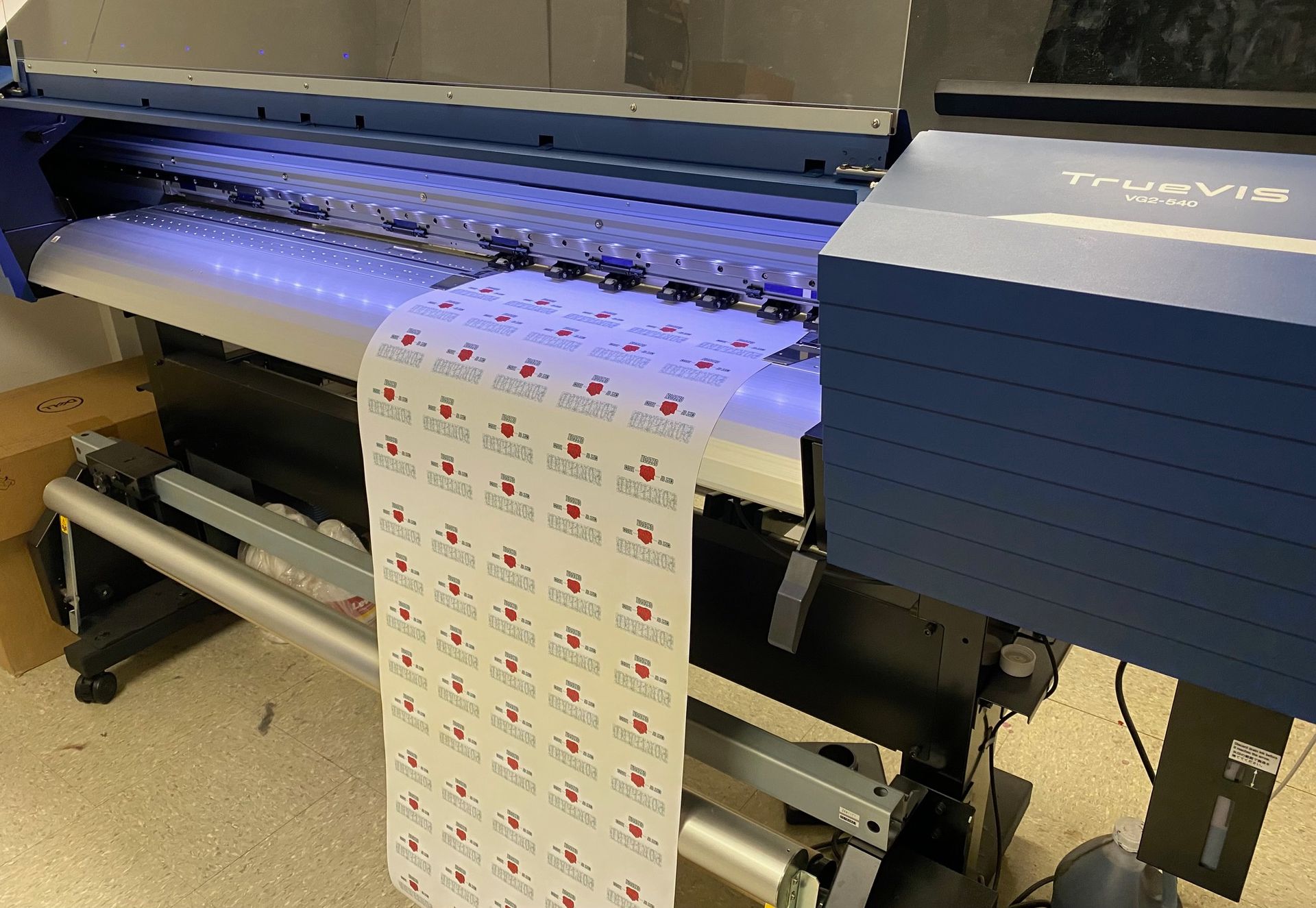 A large printer is printing stickers on a roll.