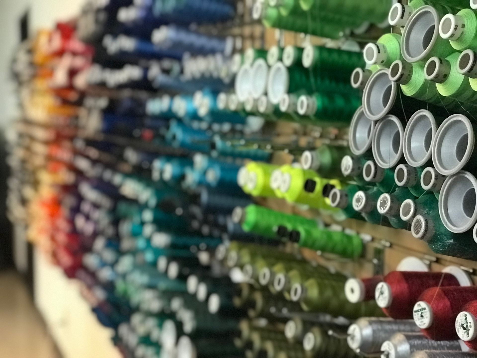 A row of spools of thread are lined up on a shelf in a store.