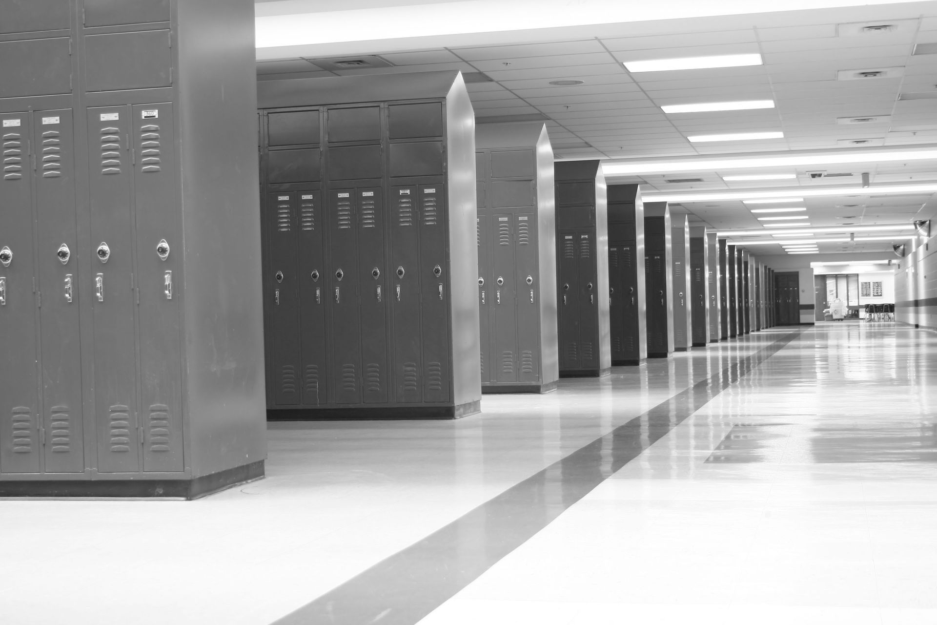 Empty school hallway with lockers, glossy floor, and bright overhead lights.