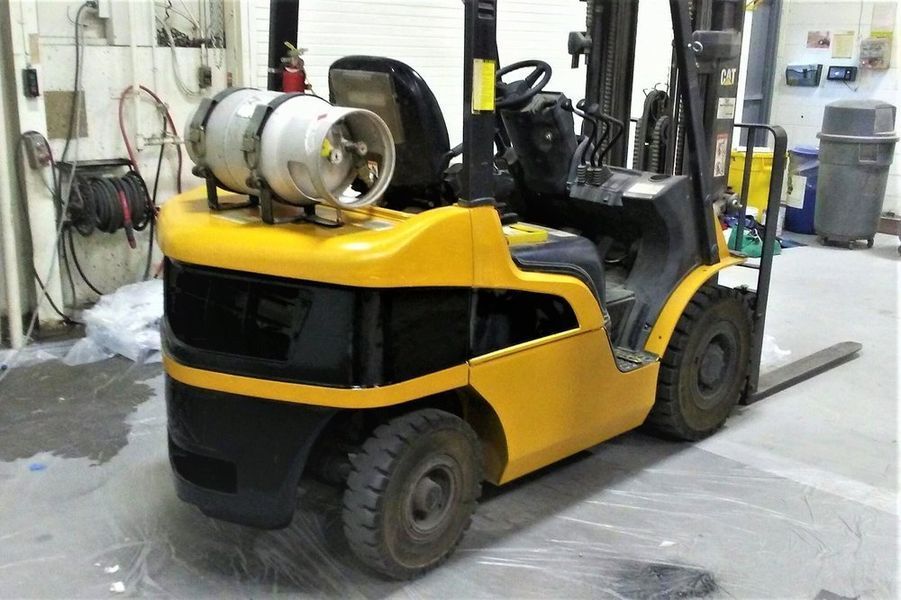 Yellow and black forklift with propane tank in a warehouse.