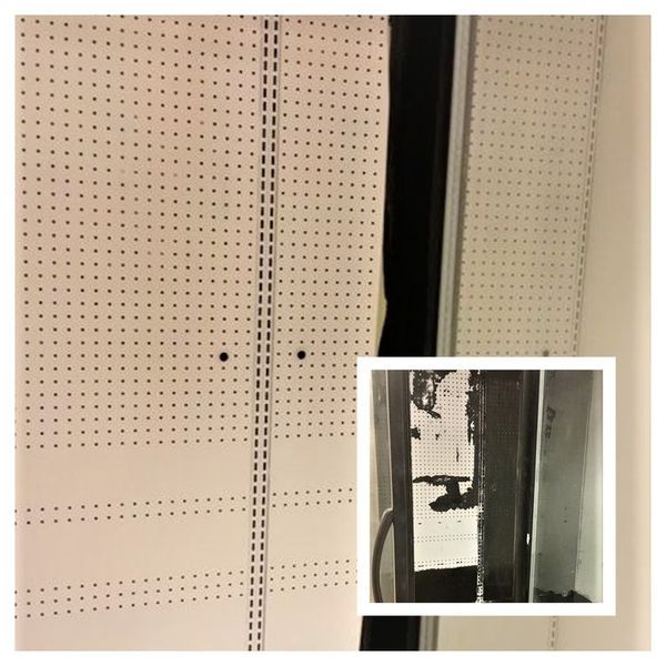 White perforated panels against a wall; a damaged black frame is inset in the corner.