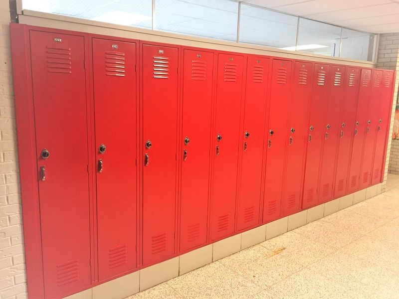 Row of red school lockers in a hallway.