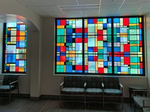 colorful stained glass windows in a waiting area with chairs
