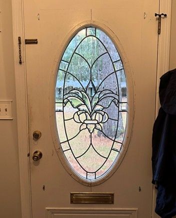 white door with an oval stained-glass window featuring a floral design, a brass mail slot is below