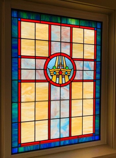 stained glass window with a cross design; center circle with architectural details, yellow and blue panels