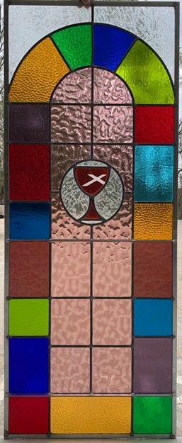 stained glass window with an arched top, colors include red, blue, green, yellow, and pink with a chalice symbol