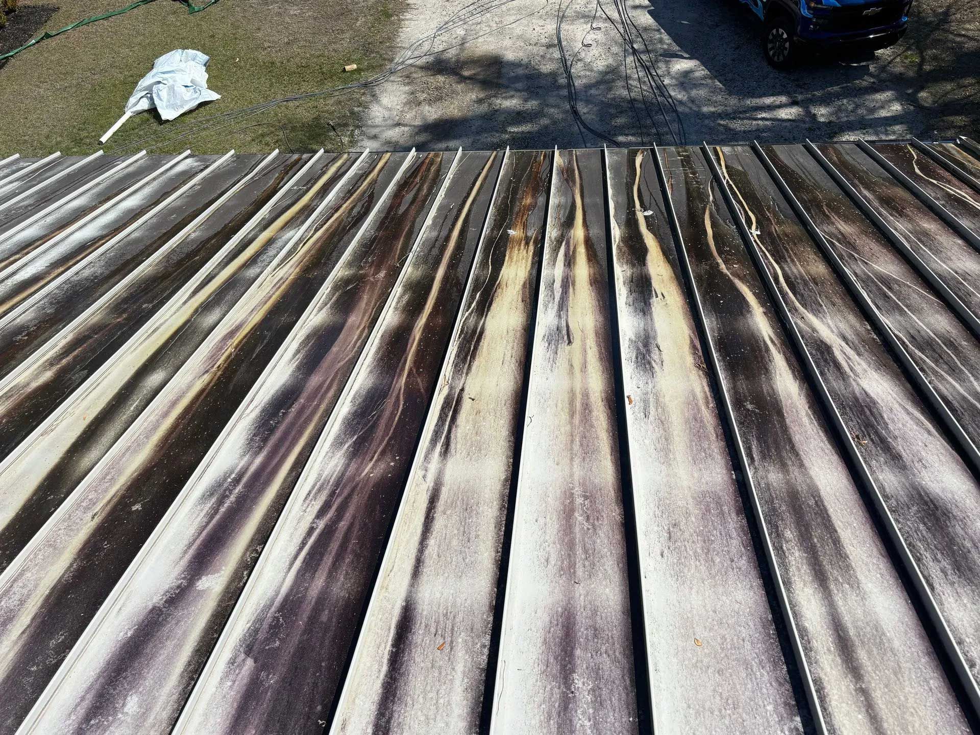 Close-up of a weathered corrugated metal roof. Brown and white streaks show weathering and staining.