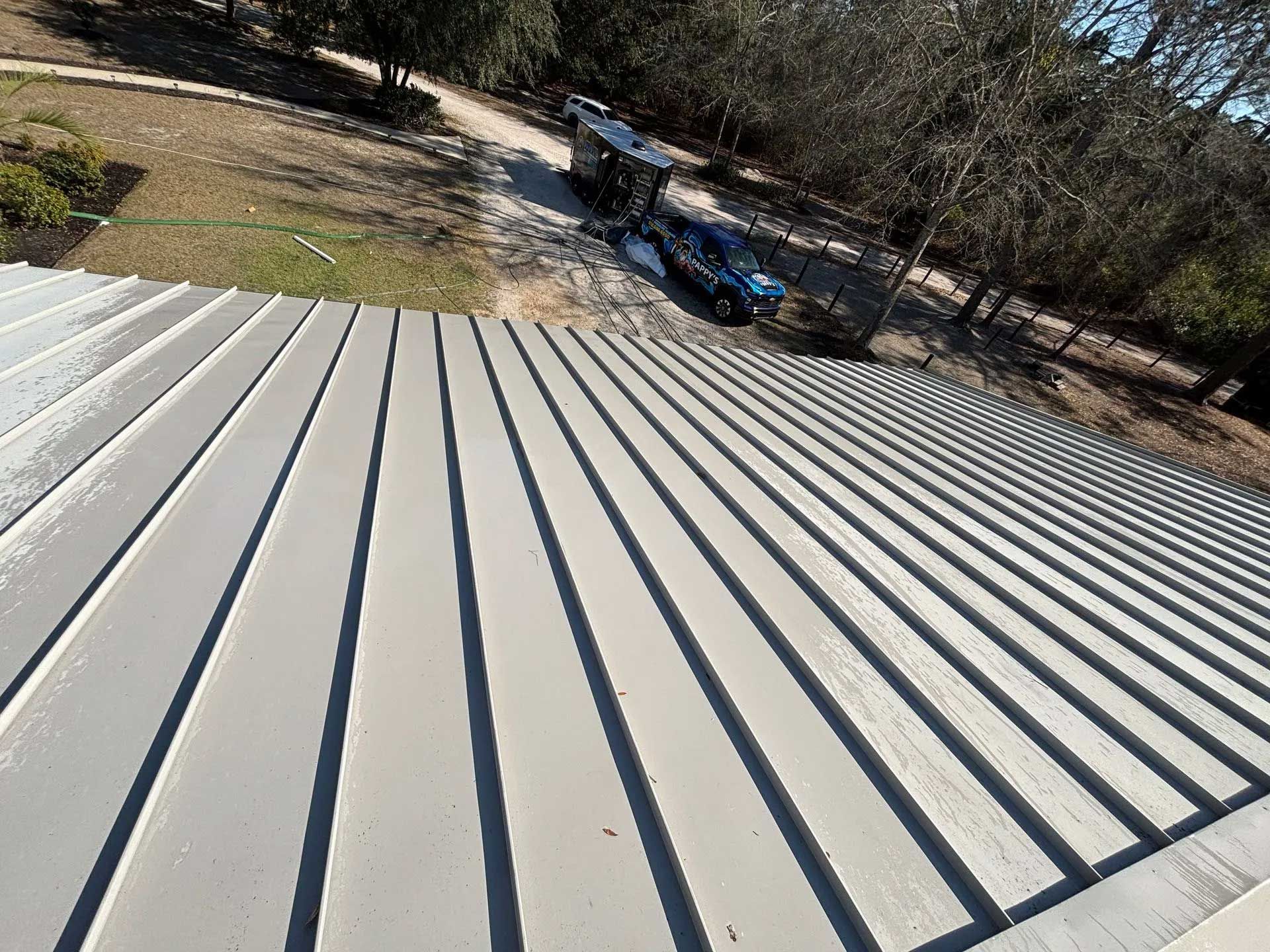 Gray metal roof with vertical lines; vehicles and trees in the background.