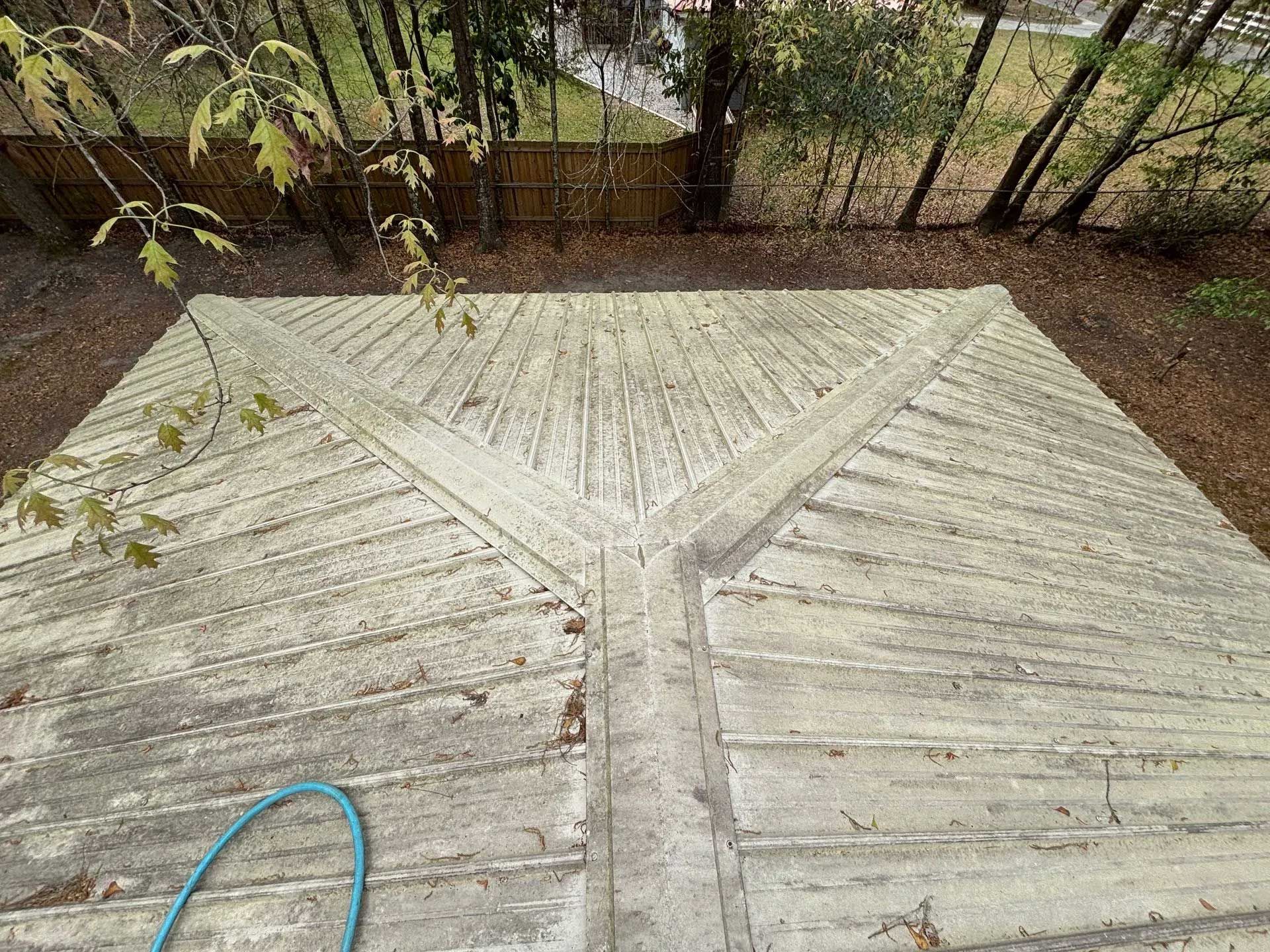 Overhead view of a concrete patio with a triangular design and weathered appearance, blue hose visible.