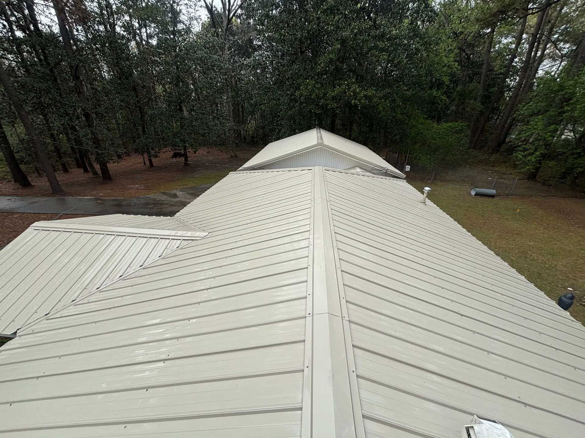 Gray metal roof with ridges, surrounded by trees and grass.