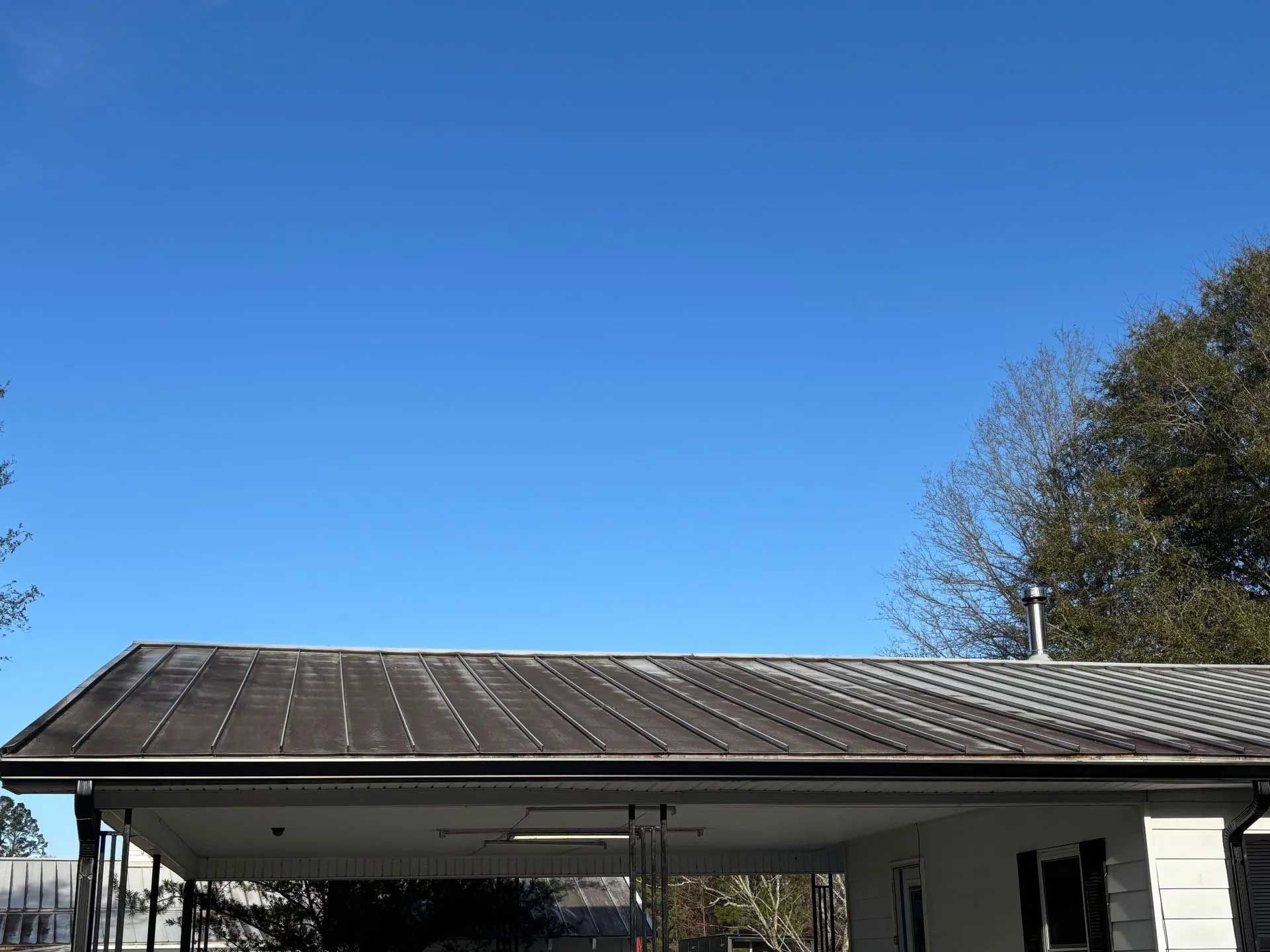 Overcast metal roof with dark streaks, under a bright blue sky.