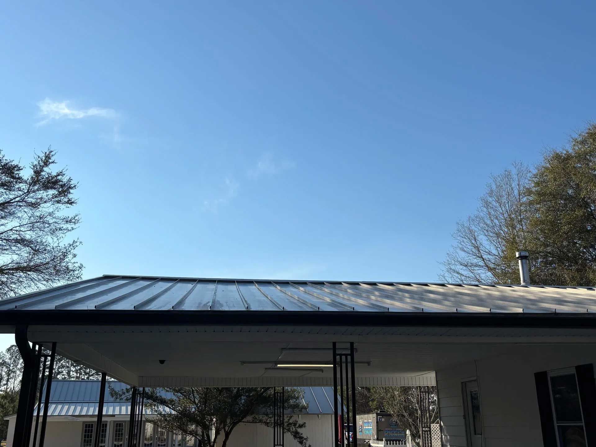 Blue sky over a building with a metal roof. A covered porch is in the foreground.