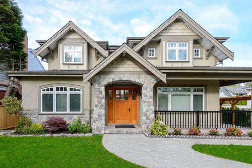 Two-story gray house with orange front door, white trim, and a curved walkway in front